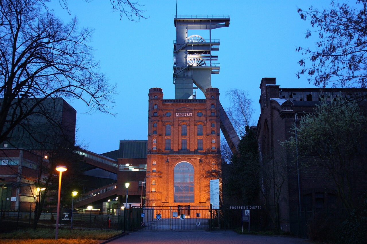 4348518862_4aafb7430c_h(1).jpg: Backsteinbau des Malakoffturms mit beleuchtetem Fördergerüst der Zeche Prosper in der Abenddämmerung