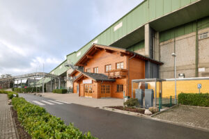 Alpincenter Bottrop: Eingangsbereich des Alpincenters Bottrop mit Holzfassade vor der großen grünen Skihalle.