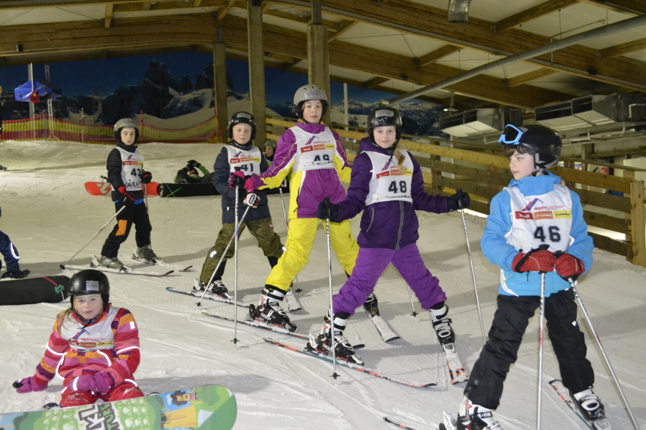 alpincenter, Bottrop: Kinder mit Helmen und Skiern üben in der Skihalle des alpincenters Bottrop auf einer Schneepiste.