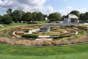 BernePark, Bottrop: Rundbecken im BernePark Bottrop mit üppiger Bepflanzung, Stegen und angrenzendem Betriebsgebäude.