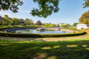 Bernepark Bottrop: Ein runder Teich umsäumt von gepflegten Hecken und Bäumen in einer parkähnlichen Anlage.