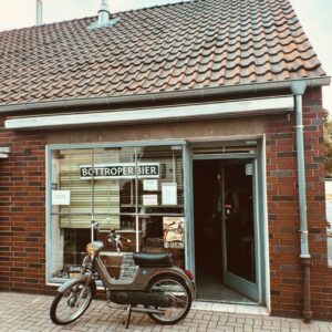 Bottroper Bier, Bottrop: Ein kleines Backsteingebäude mit einem Schild "Bottroper Bier" daneben ein altes Motorrad.
