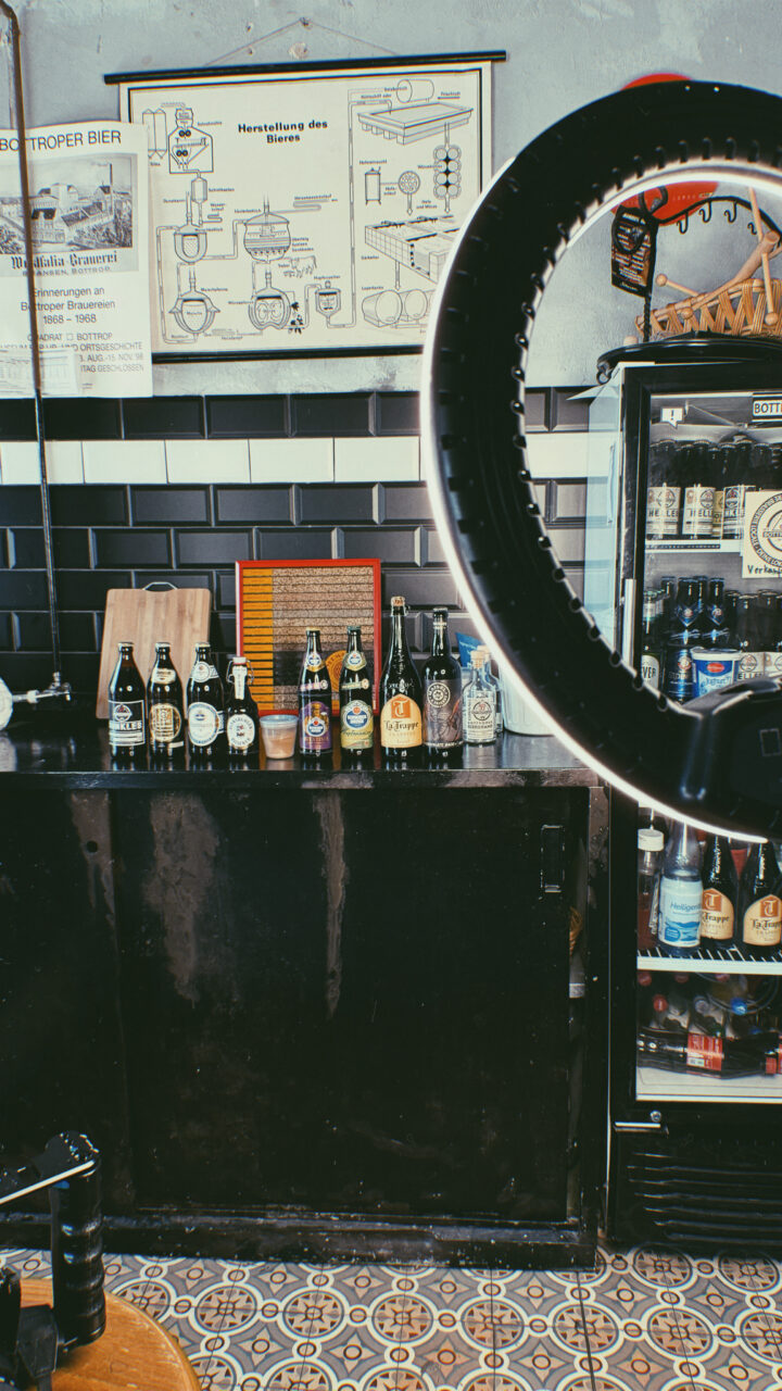 Bottroper Bier, Bottrop: Blick in eine gemütliche Bar mit verschiedenen Bierflaschen auf einer Theke und einem Regal im Hintergrund.