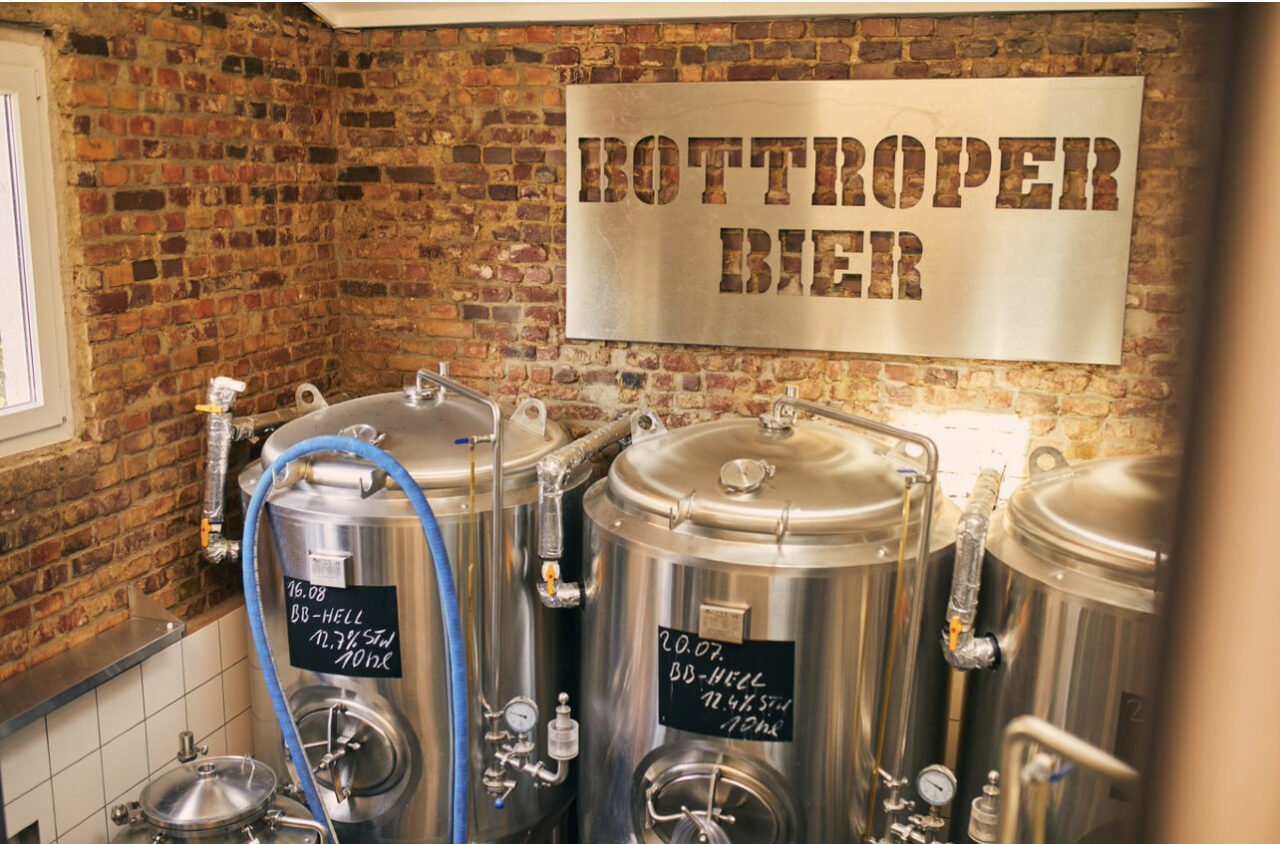 Bottroper Bier, Bottrop: Brauerei mit Metallkesseln und Schild "Bottroper Bier" an der Backsteinwand.