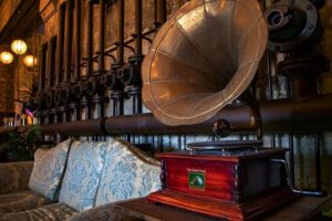 ELORIA Erlebnisfabrik, Bottrop, originalgetreue Einrichtung: Antikes Grammophon vor industrieller Wandkulisse mit Ventilen und Polstermöbeln in warmer Beleuchtung.