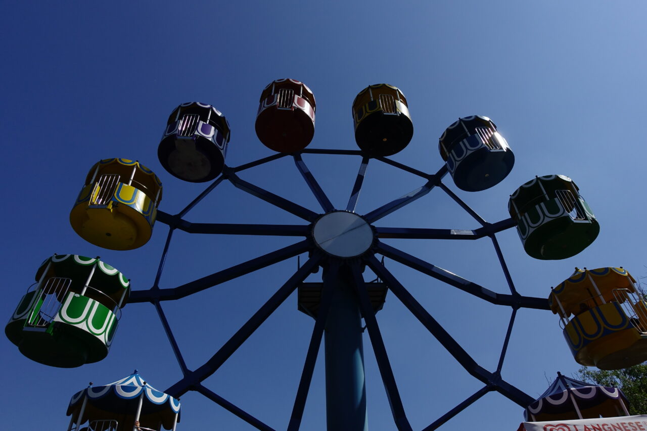 Freizeitpark Schloß Beck, Bottrop: Farbenfrohes Riesenrad mit bunten Gondeln vor klarem blauen Himmel im Freizeitpark Schloß Beck.