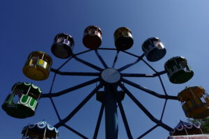Freizeitpark Schloß Beck, Bottrop: Farbenfrohes Riesenrad mit bunten Gondeln vor klarem blauen Himmel im Freizeitpark Schloß Beck.