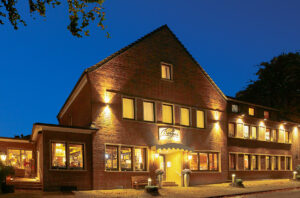 Gasthof Berger, Bottrop: Backsteinbau des Gasthofs Berger in Bottrop bei Abendbeleuchtung unter klarem dunkelblauem Himmel.