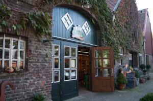 Hof Umberg, Bottrop: Eingang eines Hofladens in einem Backsteingebäude mit Efeubewuchs und offenen Holztüren.