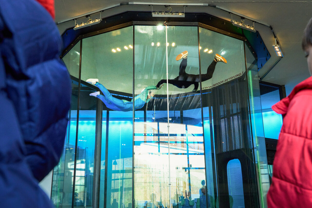 Indoor Skydiving Bottrop: Zwei Personen schweben im Windtunnel beim Indoor Skydiving Bottrop in einer gläsernen Flugröhre.