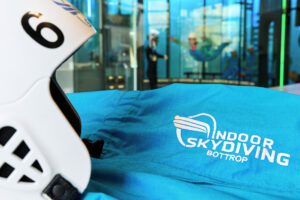 Indoor Skydiving Bottrop: Weißer Helm mit der Nummer 6 und blauer Anzug mit Logo von Indoor Skydiving Bottrop im Vordergrund.