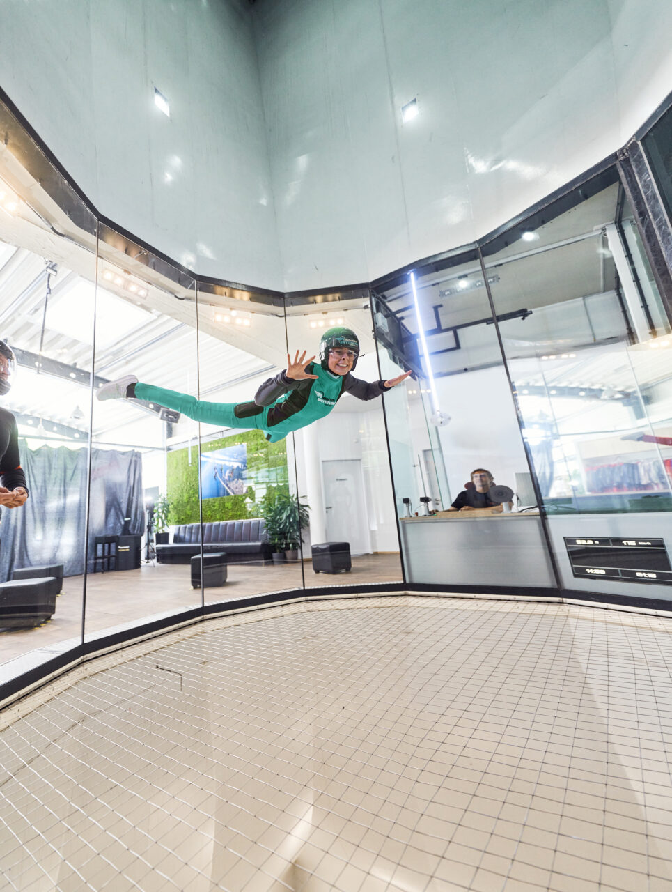 Indoor Skydiving, Bottrop, Flug: Person mit Schutzhelm und Anzug schwebt in einer vertikalen Windröhre beim Indoor Skydiving in Bottrop.