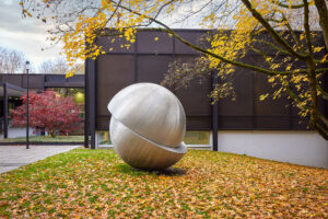 Josef Albers Museum Quadrat, Bottrop: Eine große, silberne Kugelskulptur steht auf einer herbstlich bedeckten Wiese vor einem modernen Gebäude.