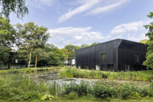 Josef Albers Museum Quadrat Bottrop 2228_klein.jpg: Modernes schwarzes Museumsgebäude am Teich, umgeben von Grünflächen und hohen Bäumen.