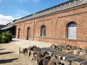 Lokschuppen, Bottrop, Außenansicht Seite: Backsteinbau des Lokschuppens Bottrop mit großen Rundbogenfenstern und moderner Glasfassade.