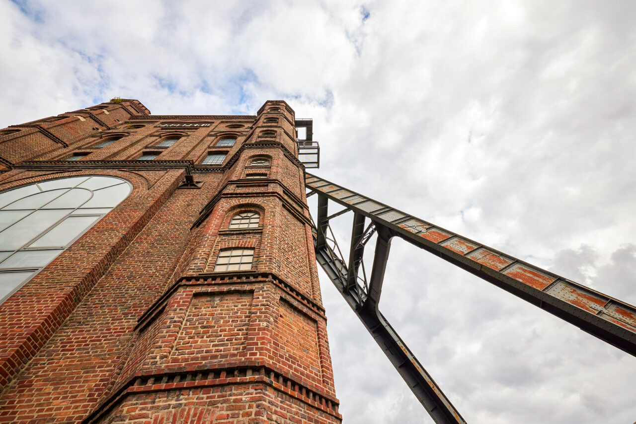 Malakoffturm Bottrop: Hoher Backstein-Industriedenkmal mit Stahlträgern vor bewölktem Himmel in Bottrop, Nordrhein-Westfalen.