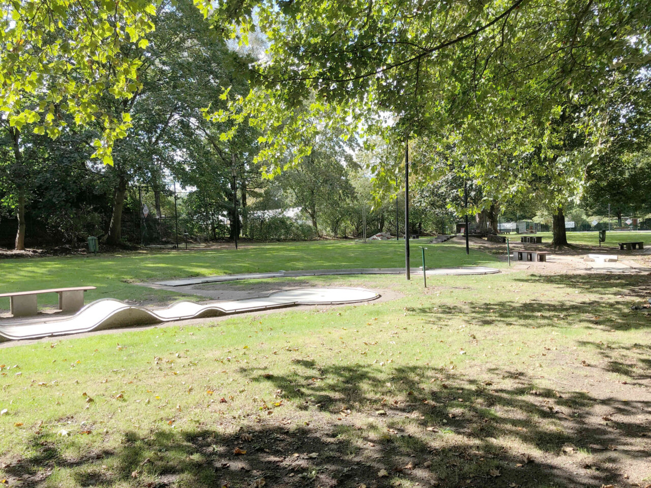 Minigolf im Stadtgarten, Bottrop: Minigolfanlage im grünen Stadtgarten Bottrop mit Bahnen, Sitzbänken und schattigen Bäumen