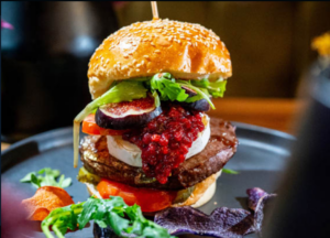 MIO1889_2.PNG: Hausgemachter Burger mit Rindfleischpatty, Feigen, Ziegenkäse, Rote-Bete-Chutney und frischem Salat