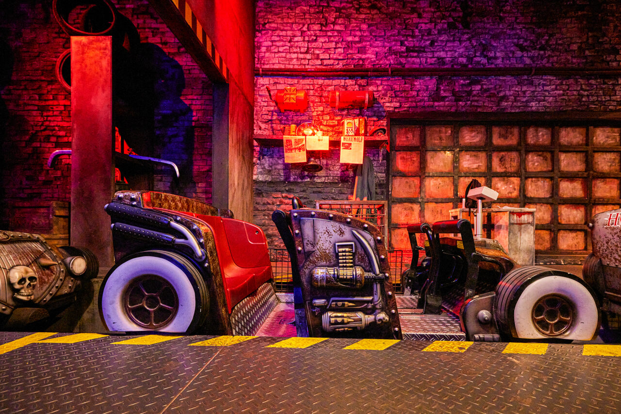 Movie Park Germany Bottrop: Futuristische Autos in einem bunten Indoor-Freizeitparkbereich mit industriellem Ambiente.