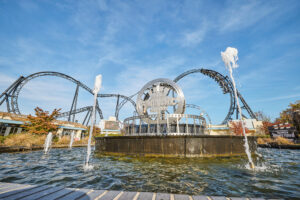Movie Park Germany Bottrop: Filmparkemblem mit Achterbahn und Springbrunnen vor strahlend blauem Himmel in Bottrop.