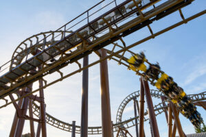 Movie Park Germany Bottrop: Achterbahn im Freizeitpark mit vorbei rauschendem, gelben Zug, Himmel im Hintergrund.