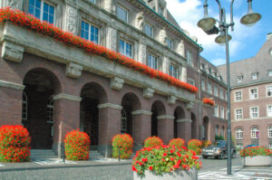 Rathaus, Bottrop, Portal, Blumen: Backsteinbau des Rathauses Bottrop mit Arkaden und roten Blumenkästen am Portal und Vorplatz.