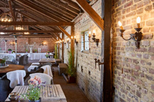 Schmücker Hof, Bottrop-Kirchhellen: Reihen von rustikalen Holztischen und gemauerten Wänden in einem großzügigen, stilvollen Raum.