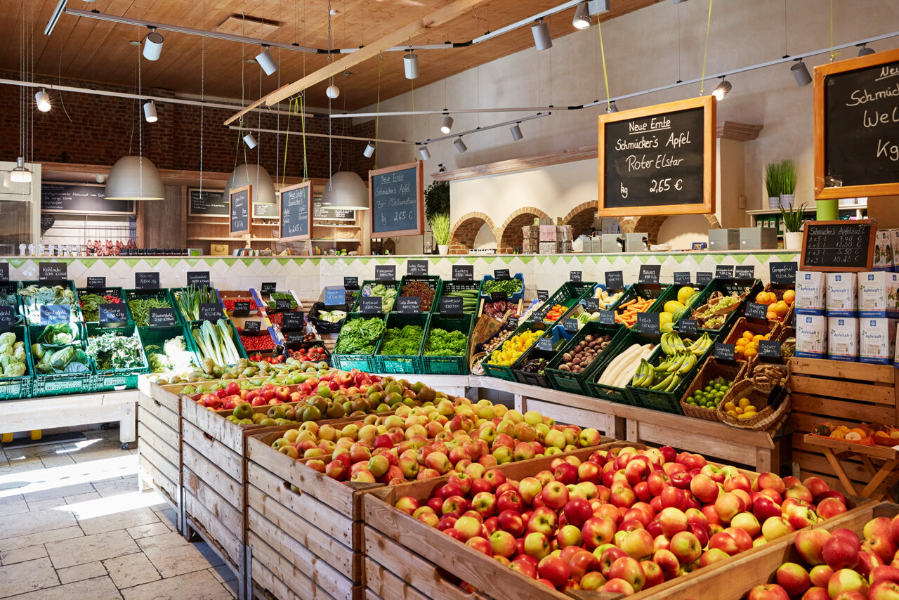 Schmücker Hof, Bottrop-Kirchhellen: Verkaufsraum mit Holzkisten voller Äpfel und Regalen mit frischem Obst und Gemüse im Hofladen.