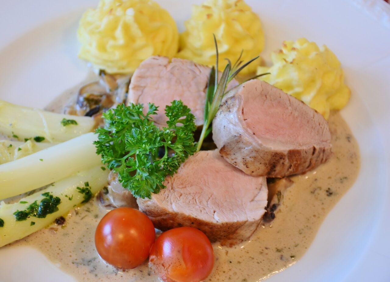 Stockfoto Edle Küche: Zartes Schweinefilet mit heller Rahmsauce, Spargel, Tomaten, Kräutern und Herzoginkartoffeln.