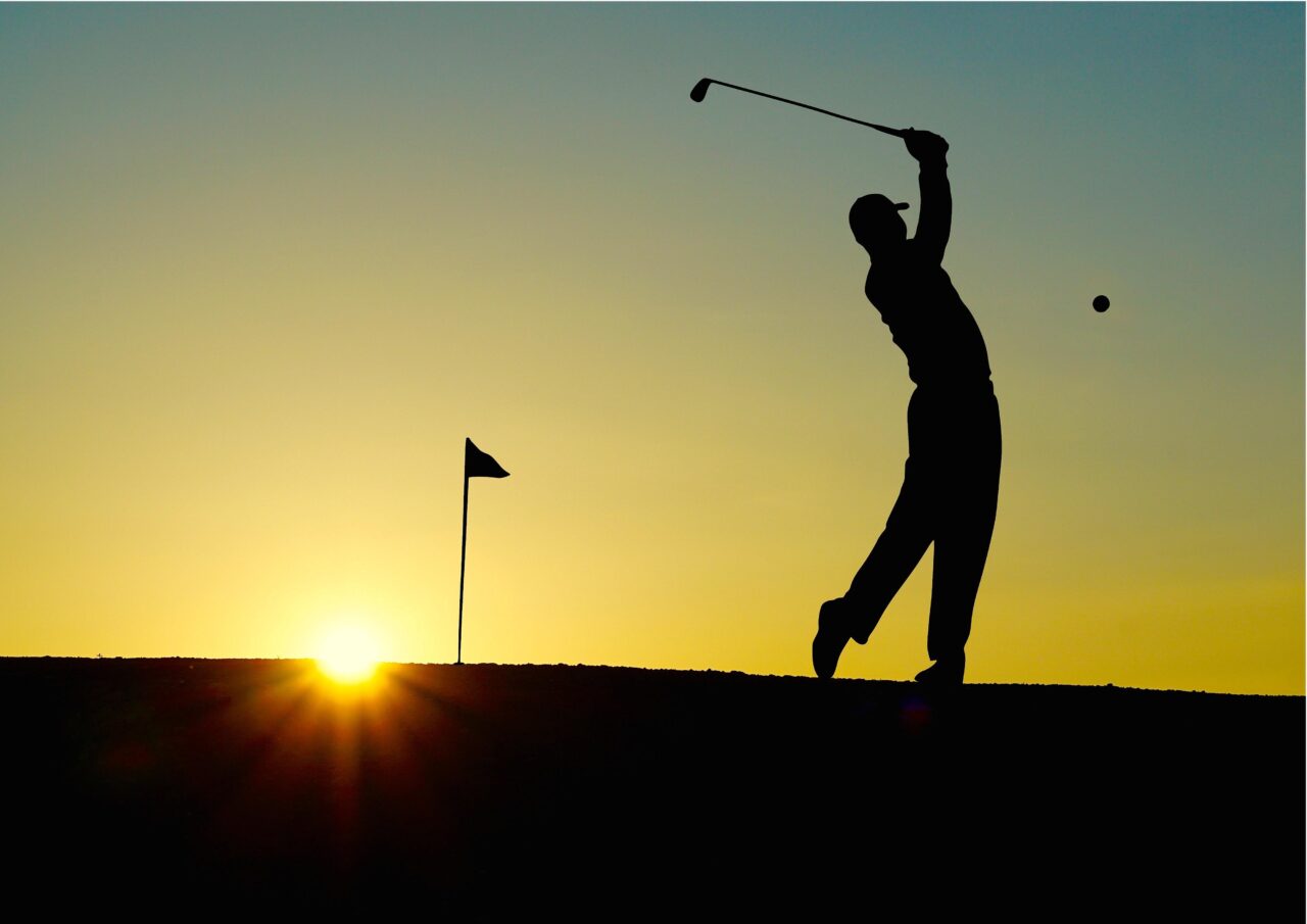 Stockfoto Golf: Golfer beim Abschlag auf dem Platz des Golfclubs Schwarze Heide vor untergehender Sonne