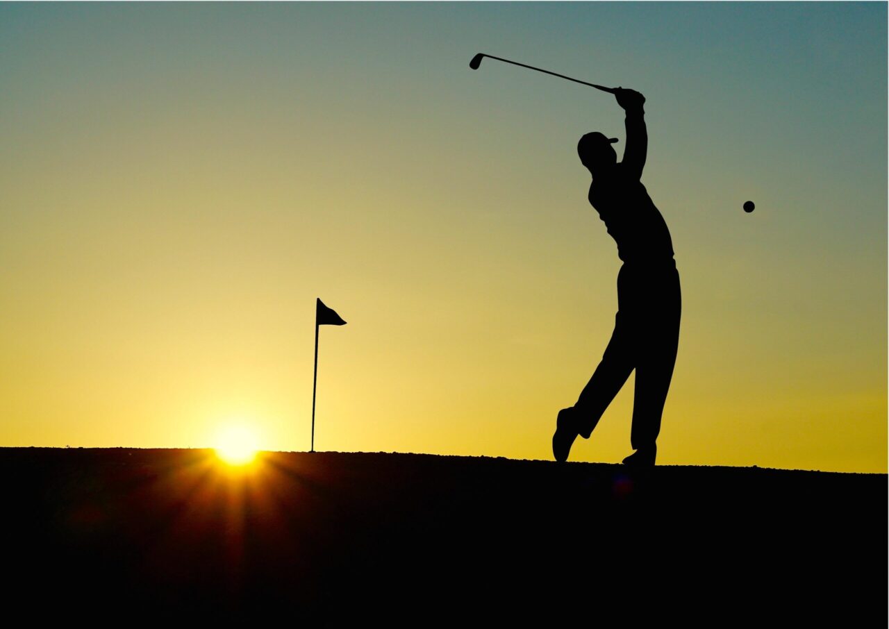 Stockfoto Golf: Golfer beim Abschlag auf dem Platz des Golfclubs Schwarze Heide vor untergehender Sonne