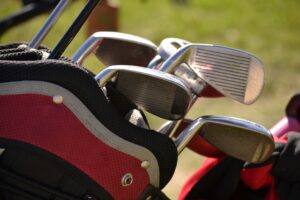 Stockfoto Golf: Golfschläger in einer rot-schwarzen Tasche vor unscharfem Hintergrund auf dem Gelände des Golfclubs.